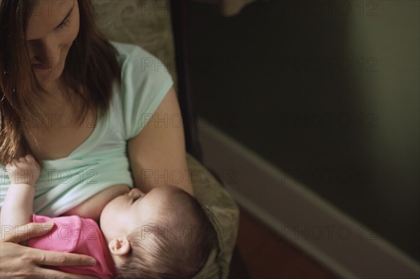 Mother breast-feeding baby in chair