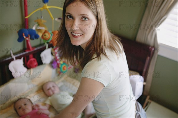 Portrait of mother and twin babies in crib