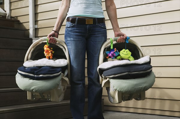 Woman carrying two baby car seats