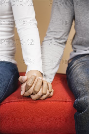 Couple holding hands on sofa