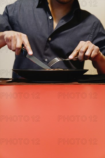 Close up of man cutting meat on plate