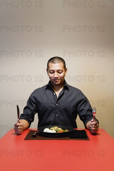 Asian man at table with full plate of food