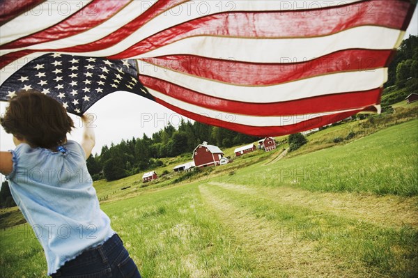 Girl running with American flag on farm