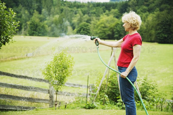 Woman watering plants with hose