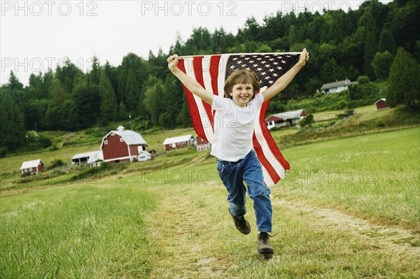 Boy running with American flag at farm