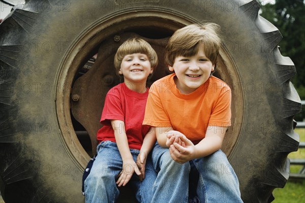 Two brothers sitting on tractor wheel