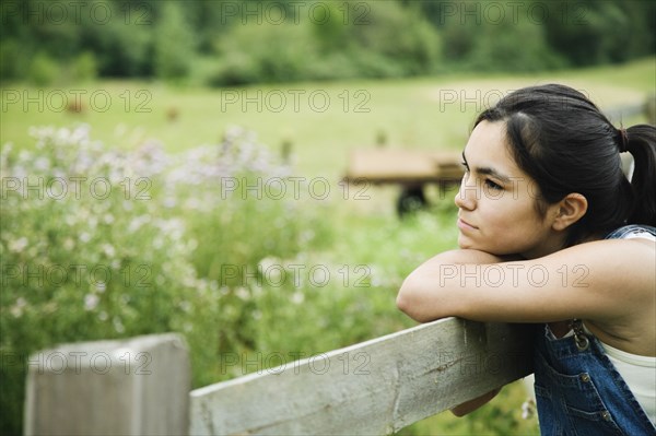 Girl leaning on wooden fence