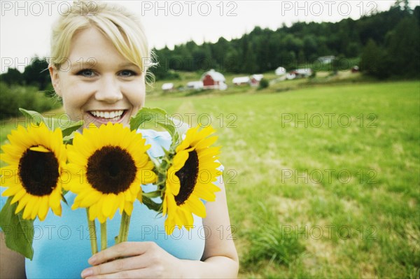 Woman holding sunflowers on farm