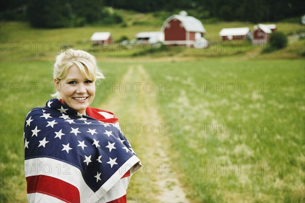 Woman on farm wrapped in American flag