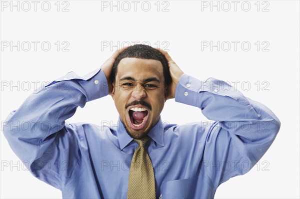 African businessman yelling with hands on head