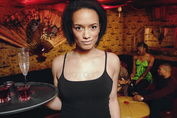 African cocktail waitress holding tray of drinks