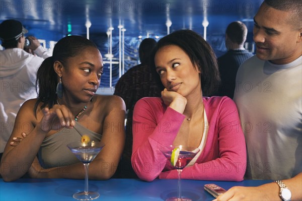 Two African women looking at each other at bar