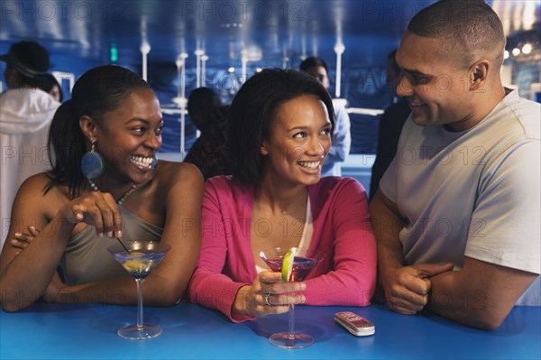 Three African friends laughing at bar