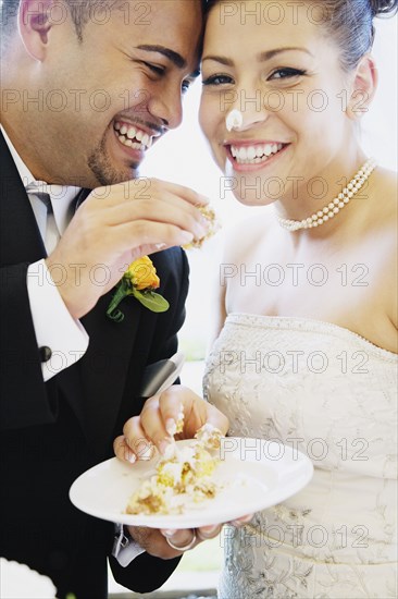 Multi-ethnic bride and groom eating cake