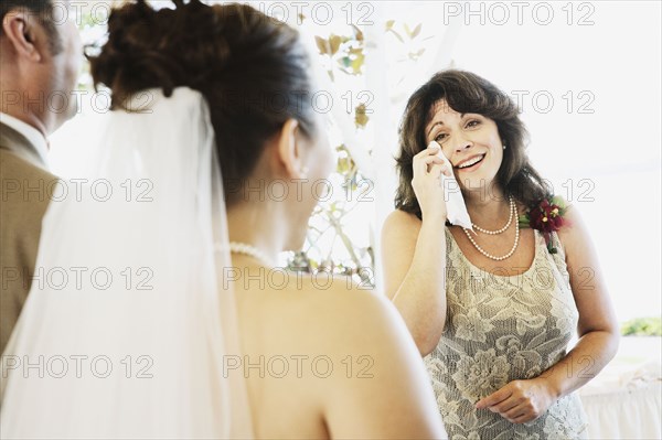 Crying woman watching bride walk down aisle