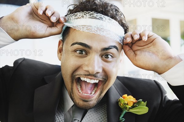 Hispanic groom wearing garter on head