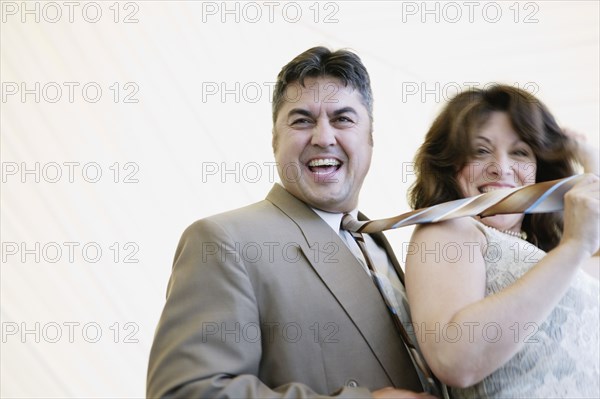 Hispanic woman pulling husband by tie