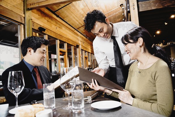 Asian couple reading menu at restaurant