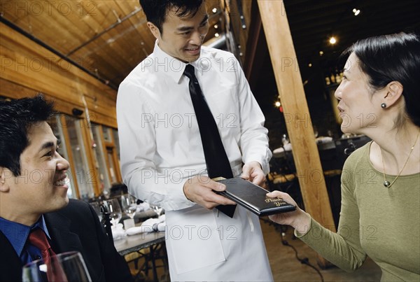 Asian couple paying restaurant bill