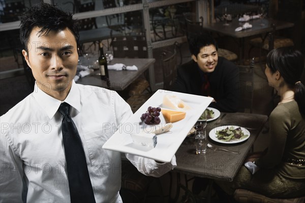 Asian waiter carrying plate of food