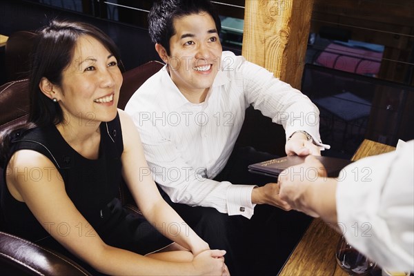 Asian couple paying restaurant bill