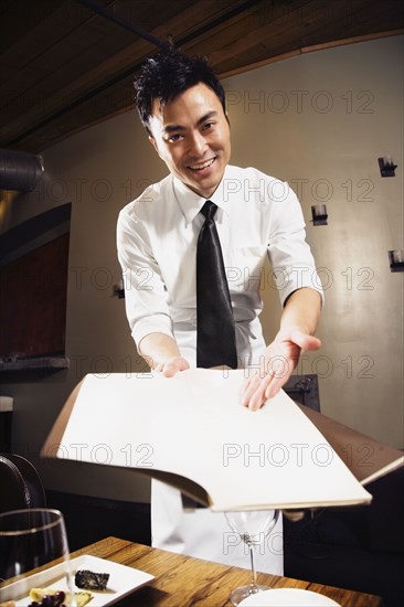 Asian waiter pointing to menu