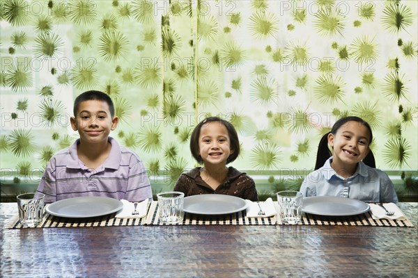 Asian siblings sitting at dinner table