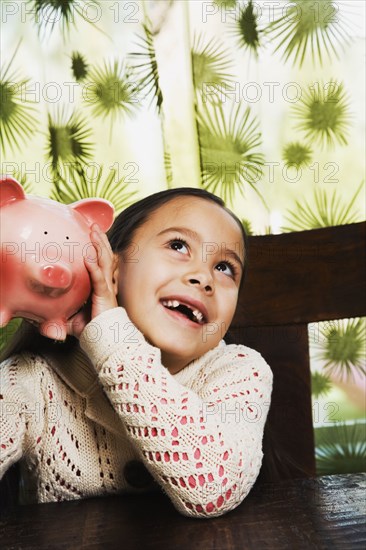 Asian girl shaking piggy bank