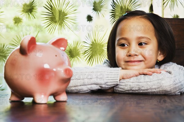 Asian girl looking at piggy bank