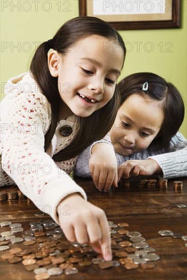 Asian sisters counting coins