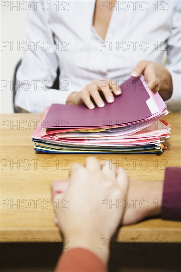 Mixed Race businesswoman with stack of folders