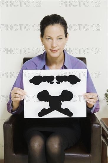 Mixed Race female psychiatrist holding ink blot