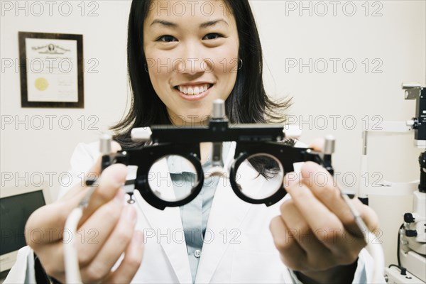 Asian female optometrist holding equipment