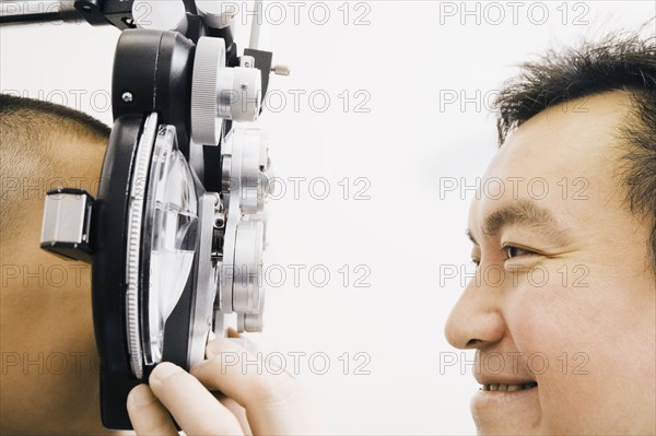 Asian male optometrist examining patient