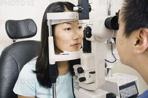 Asian male optometrist examining patient