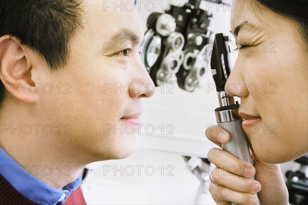 Asian female optometrist examining patient