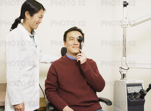 Asian female optometrist examining patient