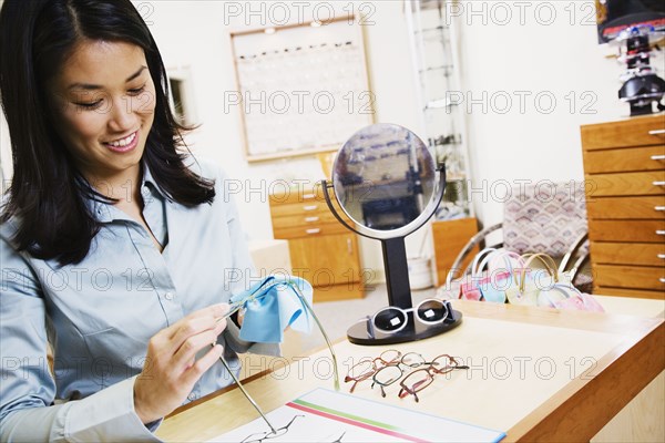 Asian optometrist cleaning eyeglasses