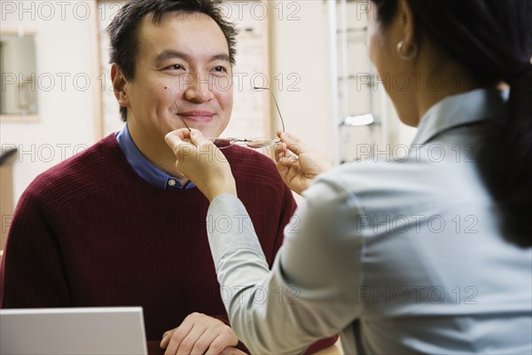 Asian man trying on eyeglasses