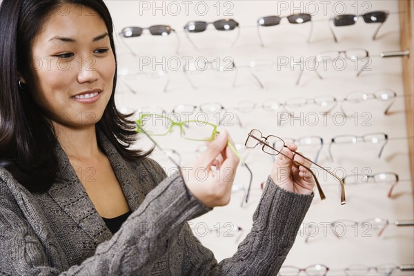 Asian woman comparing eyeglasses