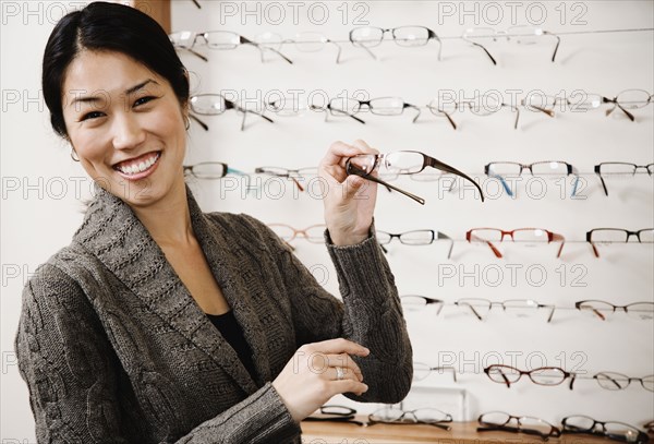 Asian woman holding eyeglasses