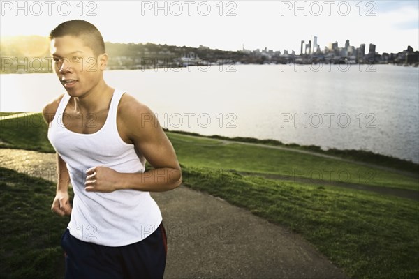 Asian man jogging along urban waterfront