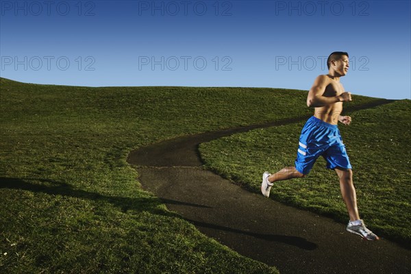 Bare chested Asian man jogging in park