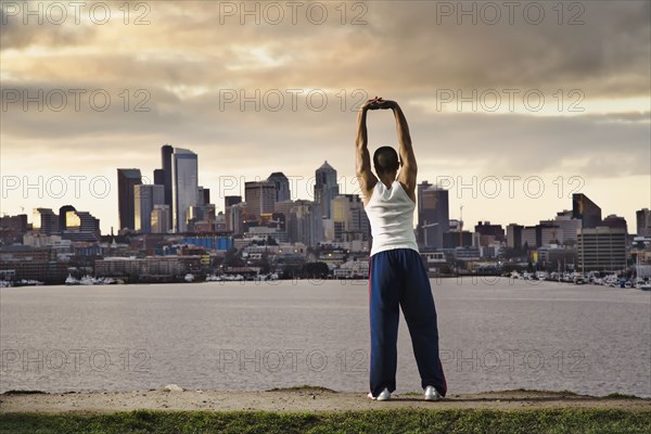 Asian man stretching at urban waterfront