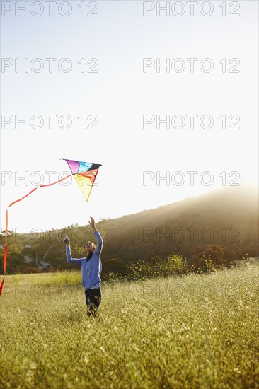 Asian woman flying kite in field