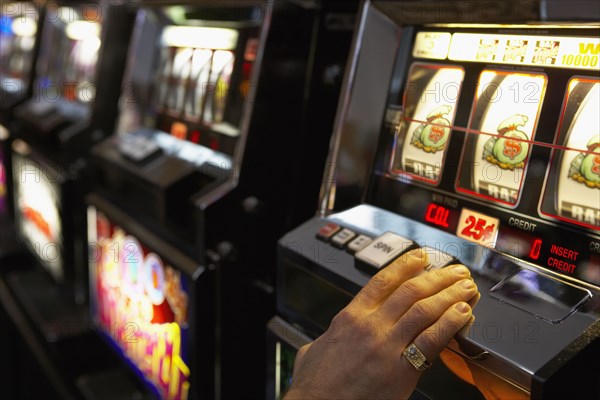 Man pushing the spin button on a slot machine - Photo12-Tetra Images .