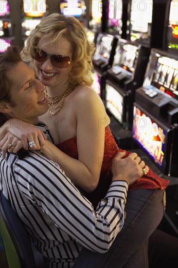 Woman sitting on her boyfriend's lap as they play the slot machines