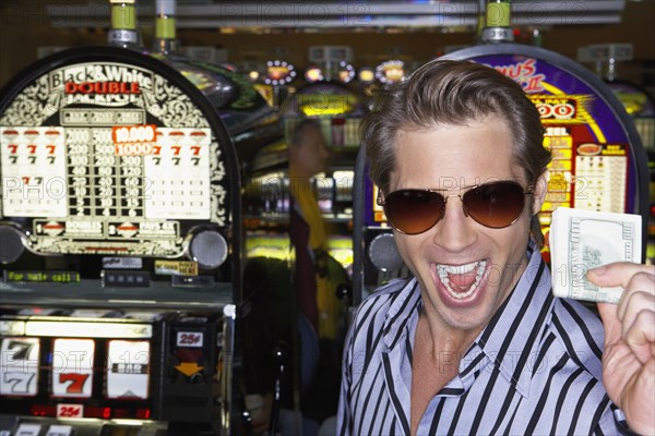 Young man holding his winnings at the casino