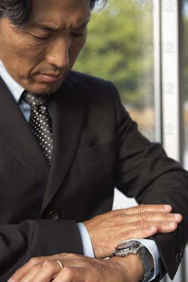 Asian businessman looking at wrist watch