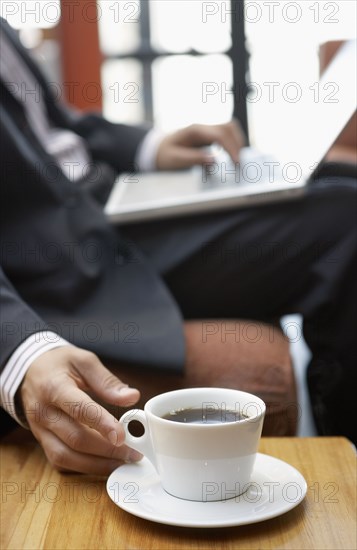 Businessman reaching for cup of coffee
